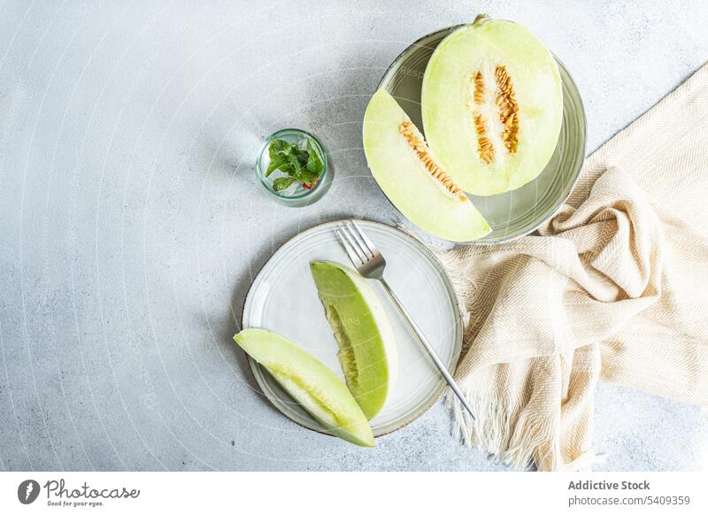 Honeydew green variety of melon fruit for dessert still life background pieces immature big drink white ceramic plate light colored glass table dish fresh