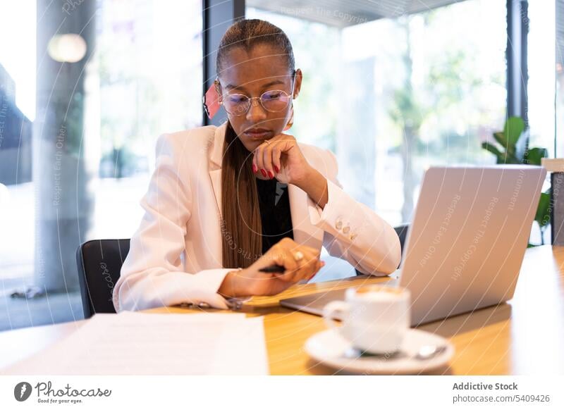 Focused woman doing paperwork in office businesswoman concentrate focus laptop coffee busy entrepreneur table workplace cup professional pensive formal ethnic