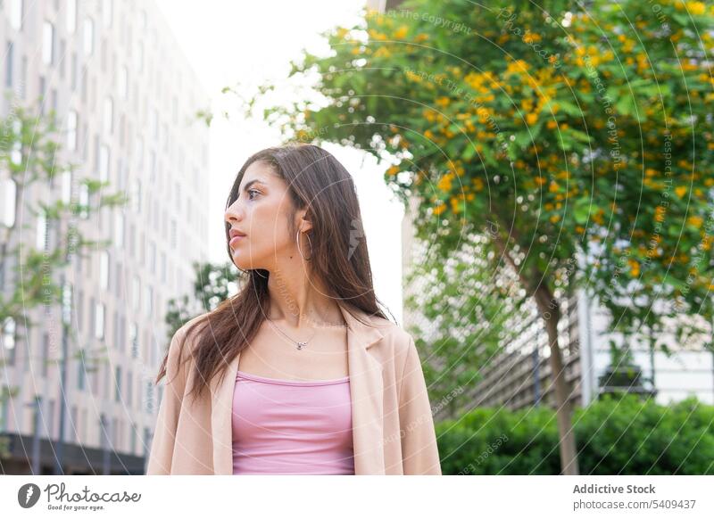 Stylish woman in blazer near building businesswoman entrepreneur formal pensive thoughtful Middle Eastern urban manager style serious glass wall young confident