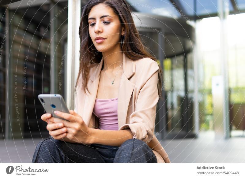 Businesswoman using smartphone near building businesswoman concentrate focus text message online texting manager city internet cellphone ethnic Middle Eastern