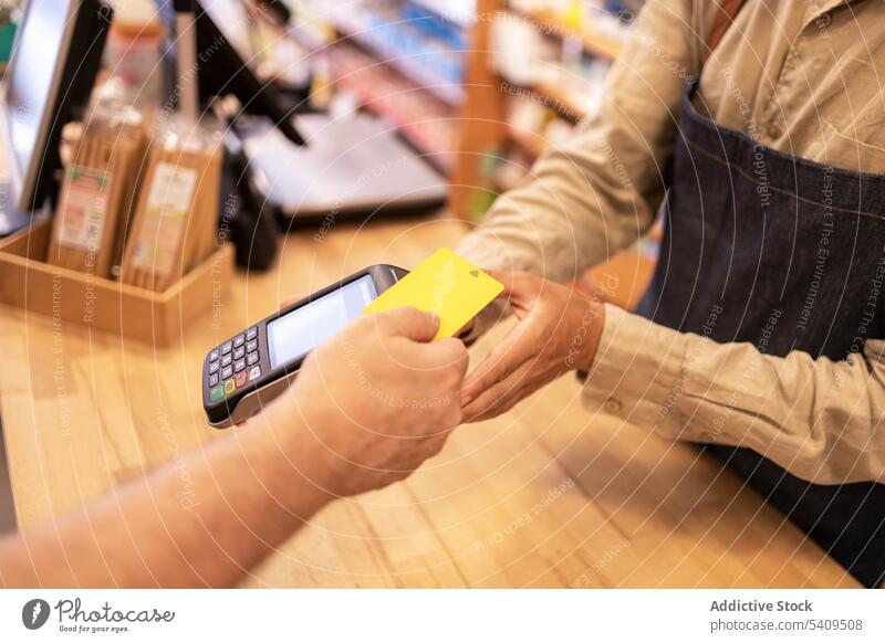 Crop man paying with credit card in drugstore payment client customer purchase transaction pos machine terminal finance device male money contactless service