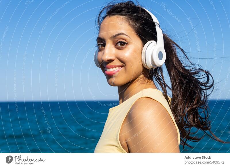 Indian woman in headphones on seashore listen smile music using rest summer song indian beach water happy young relax wave cheerful melody wireless meloman