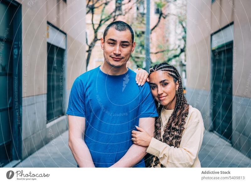 Diverse couple on street of old town boyfriend girlfriend smile positive braid appearance hug city romantic embrace relationship outfit hispanic woman happy