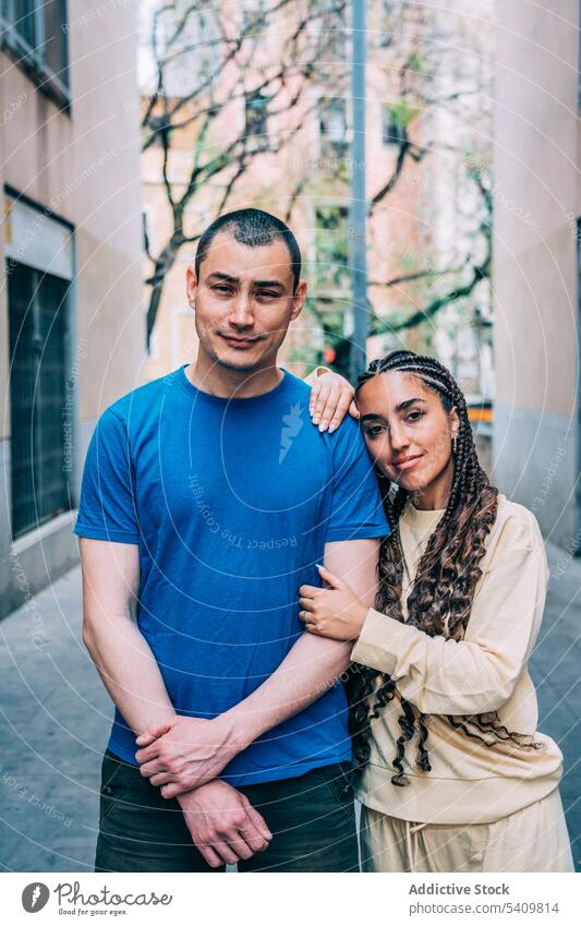 Diverse couple on street of old town boyfriend girlfriend smile positive braid appearance hug city romantic embrace relationship outfit hispanic woman happy