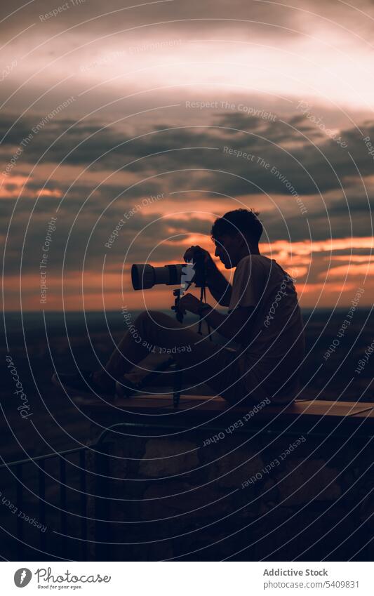 Unrecognizable man with camera taking picture of the evening orange sky with black clouds take photo sunset nature summer background male dark aim silhouette