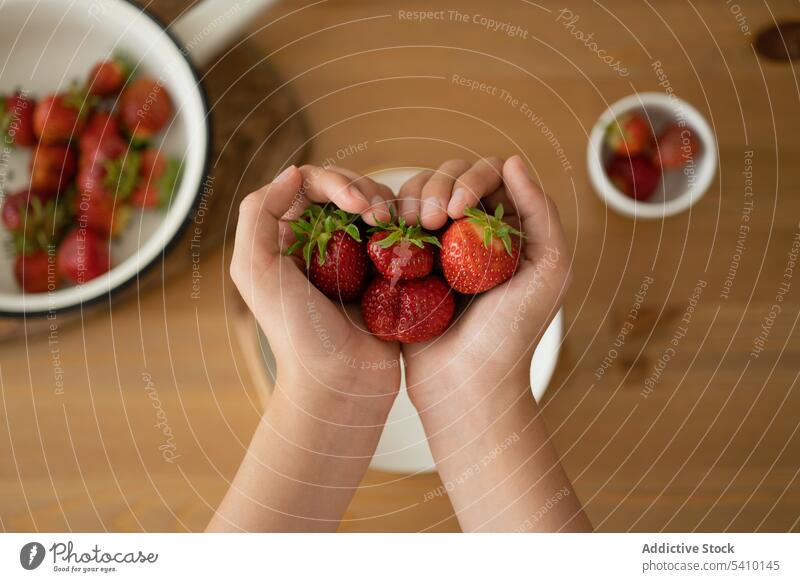 Crop person with strawberries in hands above bowl strawberry table handful fresh ripe vitamin delicious fruit natural organic demonstrate healthy food tasty