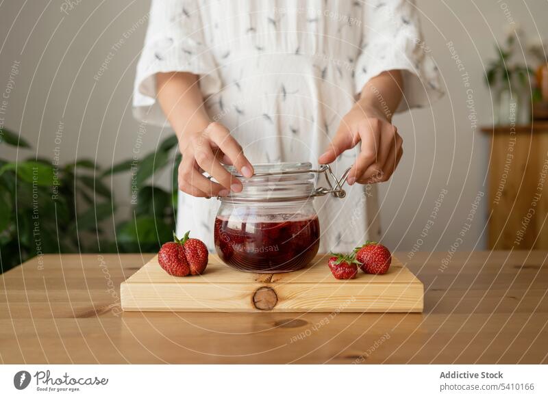 Crop woman with strawberry jam on wooden table jar tasty delicious kitchen breakfast healthy fresh casual sweet homemade glass yummy ingredient fruit nutrition