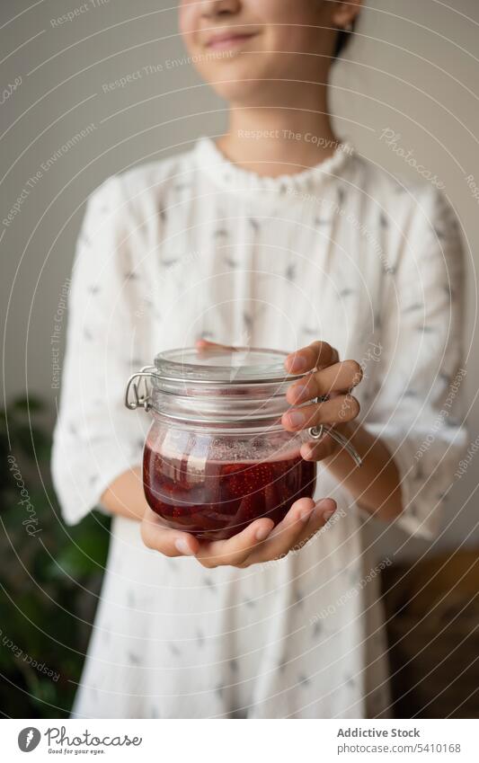 Crop woman with jar of strawberry jam positive smile glass food beverage delicious casual tasty fresh sweet room cloth happy female lady young glad enjoy home