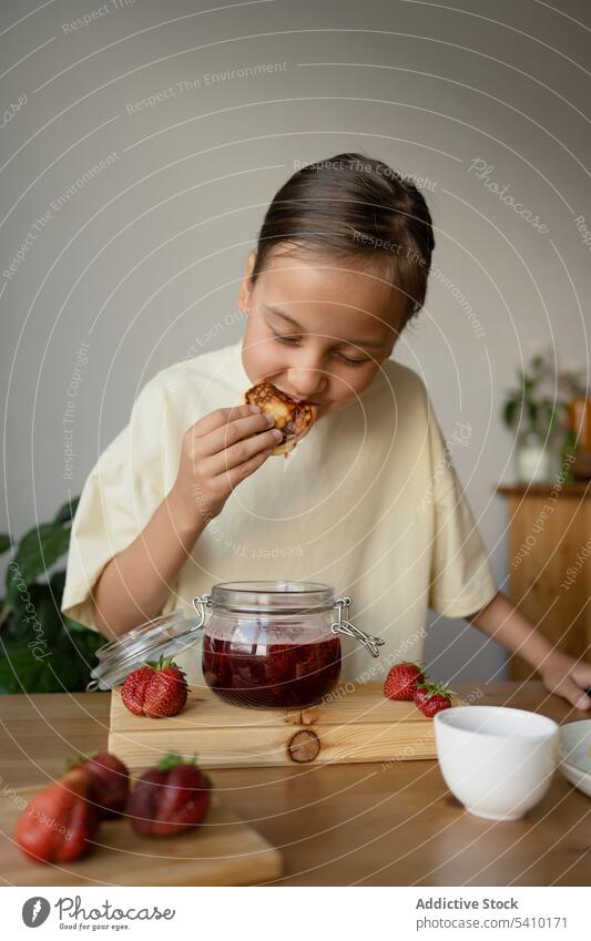 Cute girl eating pancake with fresh strawberry jam breakfast food fruit sweet tasty meal homemade yummy kid table natural preteen closed eyes delicious slice