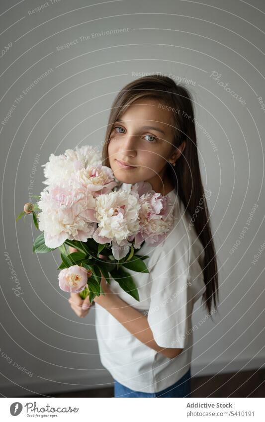 Calm preteen girl child standing with blooming peony flower with stem dreamy gentle blossom portrait delicate kid tender childhood floral charming adorable