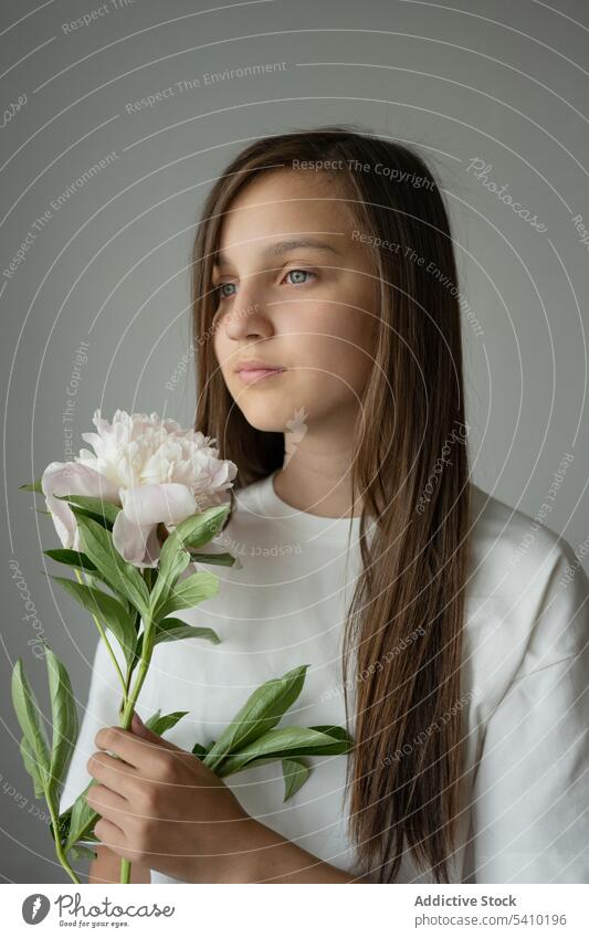 Calm preteen girl child standing with blooming peony flower with stem dreamy gentle blossom portrait delicate kid tender childhood floral charming adorable