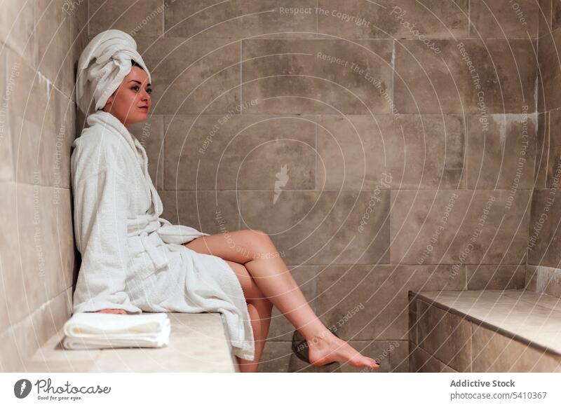 Young woman wearing bath clothes with head towel sitting down bathrobe bathroom terrace routine spa hygiene resort vacation rest female relax hammam young