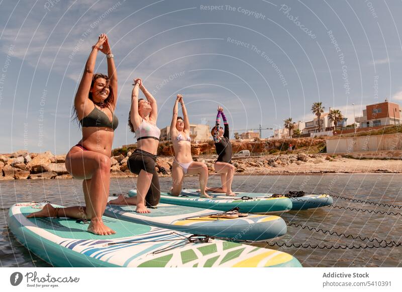 Group of women doing yoga in warrior 1 pose beach stretch practice balance warrior pose exercise activity coast kneel position wellbeing female ocean wellness