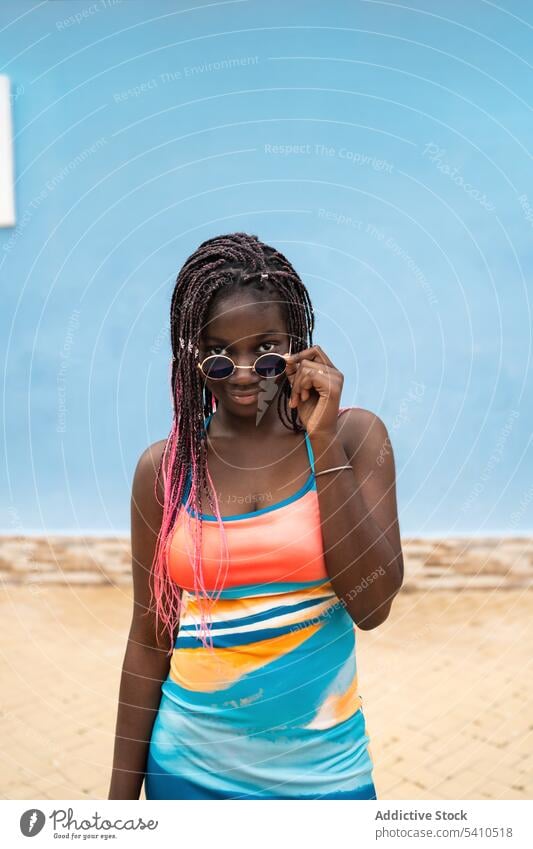 Black woman in sunglasses on blue wall summer outfit trendy style street stand confident young eyewear female braids portrait sensual afro elegant lifestyle