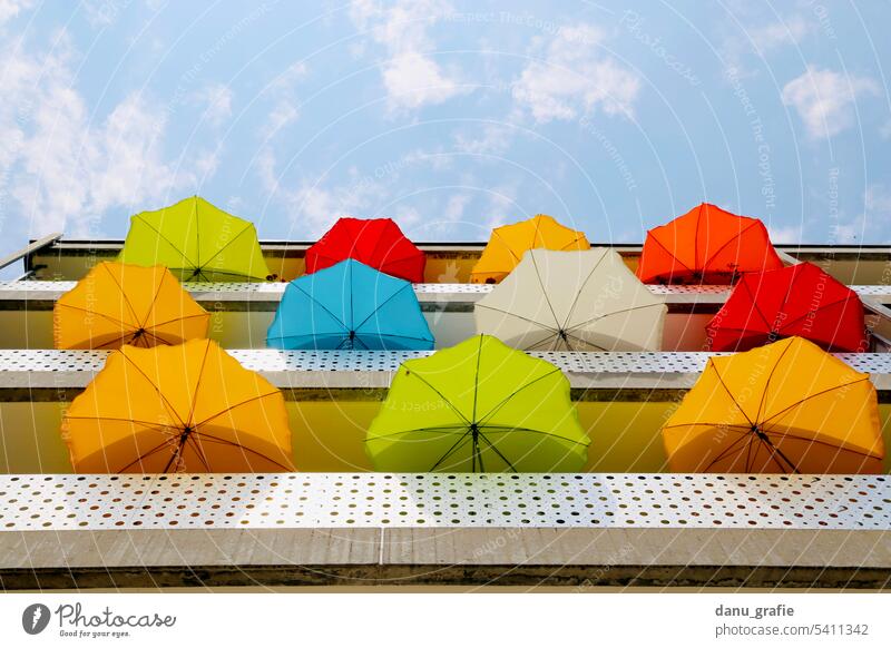 Many colorful parasols on balconies with view from below several parasols sun protection heat protection Summer Beautiful weather Exterior shot Orange Green Red