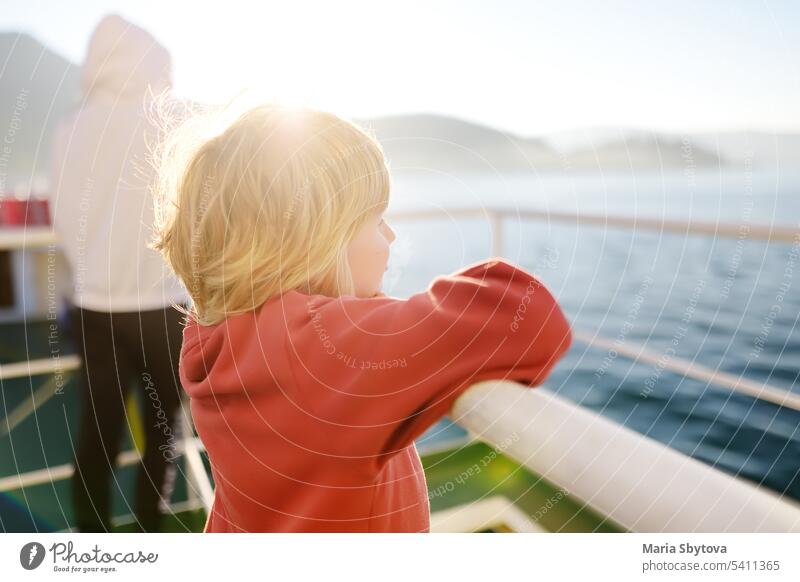 Blond little child is traveling with family by ferry or ship. Schoolboy is admiring the landscape of the Adriatic Sea. Cruise during the holidays. cruise board