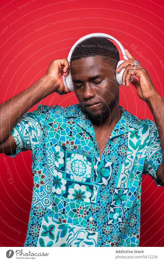 Happy African American guy playing music in headphones man listen song audio enjoy wireless melody trendy using sound african american device style headset male