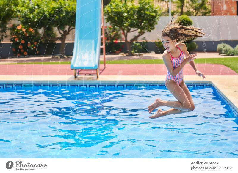 Girl jumping into pool water with trees on poolside girl summer swim vacation cheerful resort smile dive enjoy motion happy activity female holiday splash