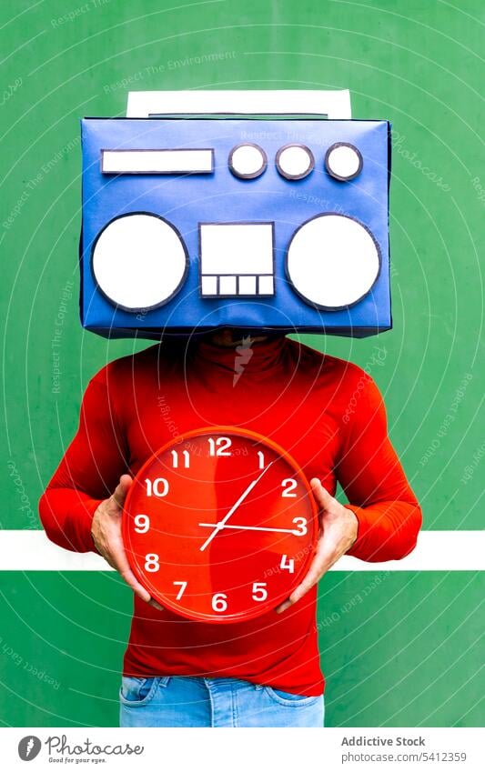 Anonymous person with boombox and clock in studio man cover face time music listen concept hide deadline hour minute punctual casual bright individuality red