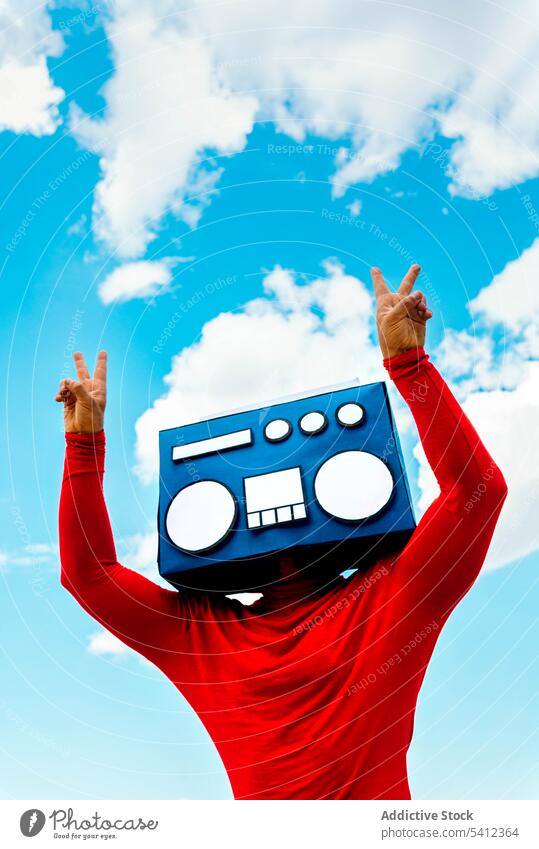 Man with boombox showing victory signs against sky man v sign peace gesture cover face listen music two fingers male blue sky casual demonstrate red cloudy