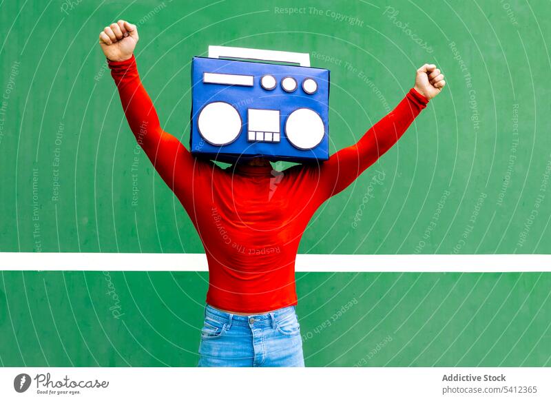 Excited faceless man with boombox raising hands cover face win celebrate arms raised hide success music listen leisure freedom individuality style male casual