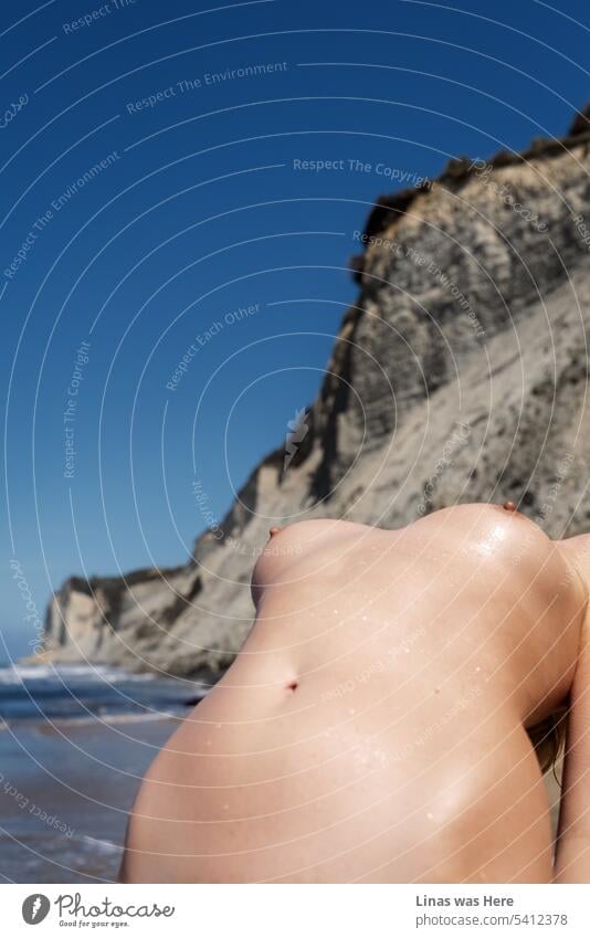 On a hot sunny summer day, this gorgeous naked girl is making the temperature rise even more. Her nude sexy curves are all over the image. She definitely outshines the magnificent coastline with majestic mountains up there.