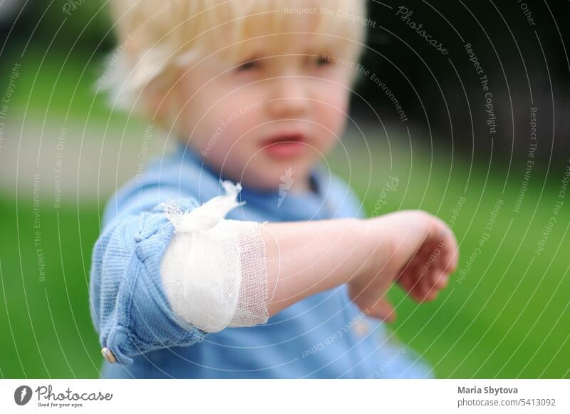 Cute little boy looking on his elbow with applied bandage. Child first aid. child wound bruise hurt kid medical gauze safety injury cut accident sports sprain