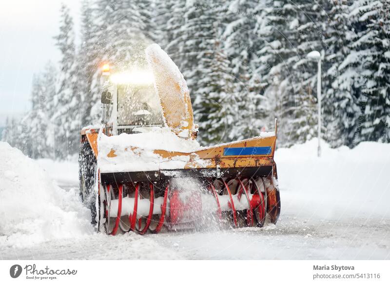 A snowplow truck clearing a snow-covered road in the European Alps while a snowstorm. Drifts and snow drifts during a snowfall. winter car snowblower alps