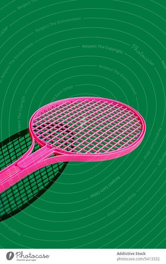 Pink tennis racket on green surface trendy color sport equipment creative style bright hobby set design object colorful contemporary art minimal simple activity