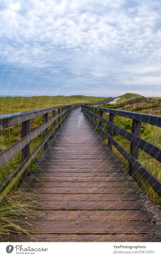 Wet wooden footpath on Sylt Island, in Germany. adventure autumn beautiful bridge climate clouds cloudy coast color dunes europe germany grass green hills