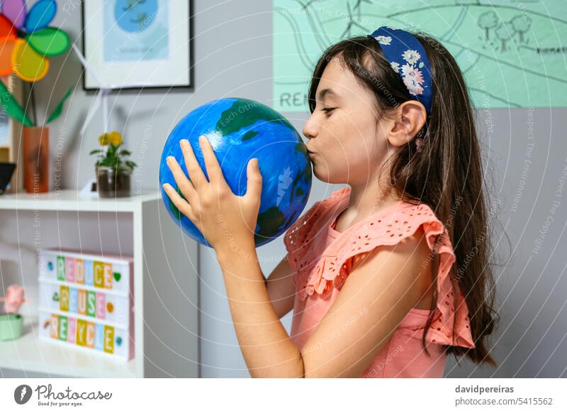 Female student kissing a handmade globe world at ecology classroom earth planet female love little girl school funny happy education sustainable ecologic global