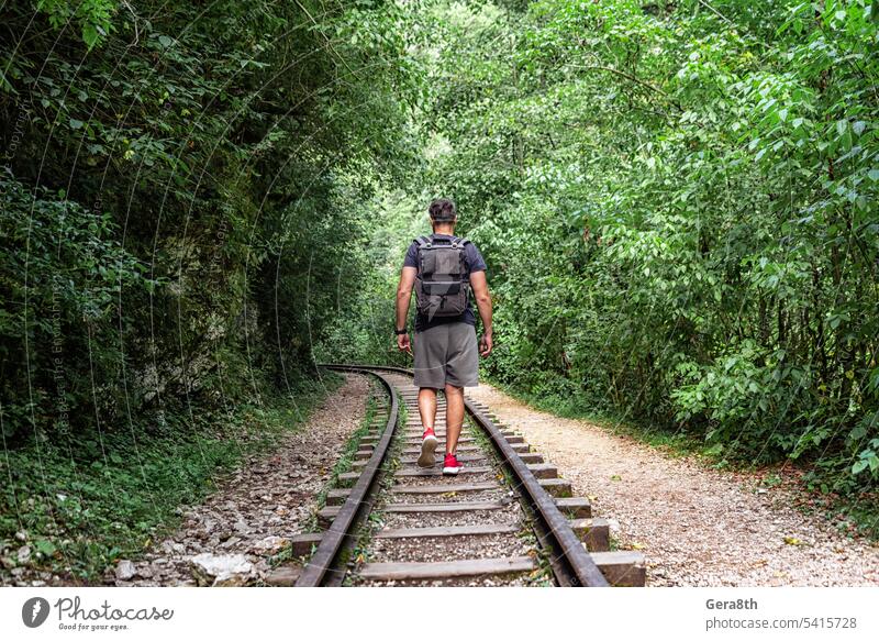 young male tourist walks on the railway in the jungle of thailand adventure backpack climate fitness forest freedom fresh go green health hiking journey