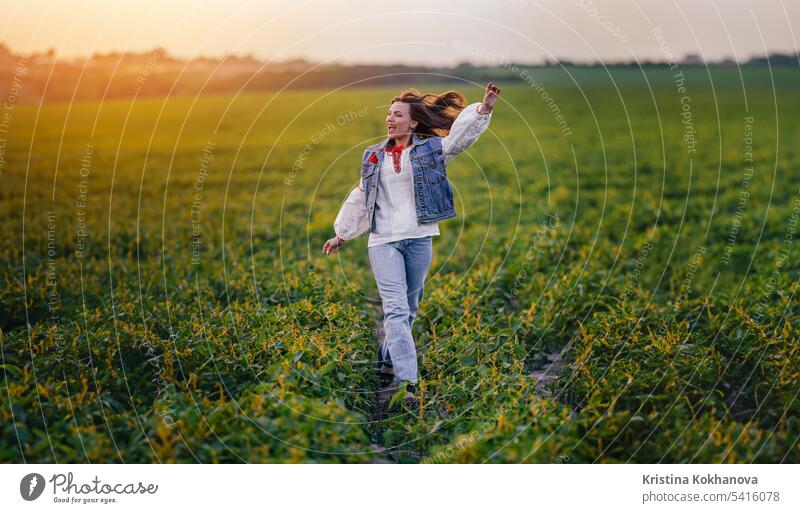 Happy woman running in green field. Young lady in white embroidery ethno shirt. happy ukrainian young beautiful beauty female girl person stylish portrait