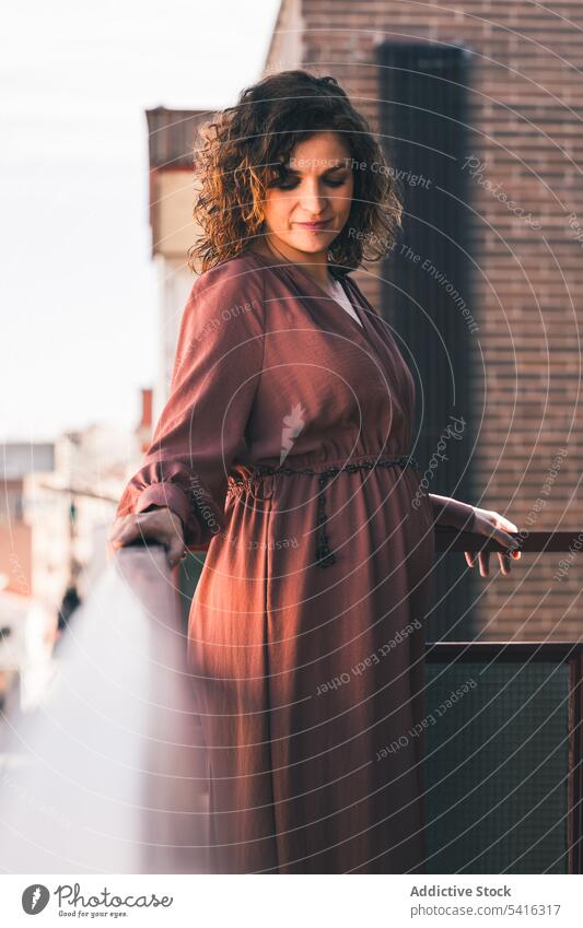 Attractive woman on balcony attractive young curly hair beautiful city urban female positive lifestyle relax casual leisure summer home elegant fashion pleasure