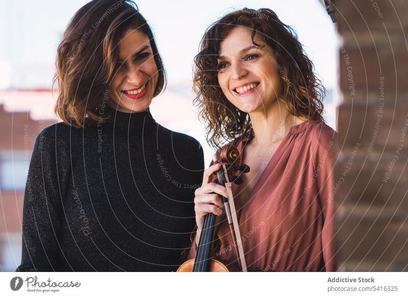 Young smiling women with violin on balcony woman musician young elegant friend instrument cheerful art sound playing performance female melody violinist