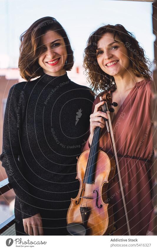 Young smiling women with violin on balcony woman musician young elegant friend instrument cheerful art sound playing performance female melody violinist