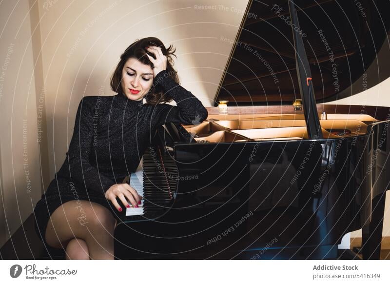 Young woman sitting at a piano posing - a Royalty Free Stock Photo