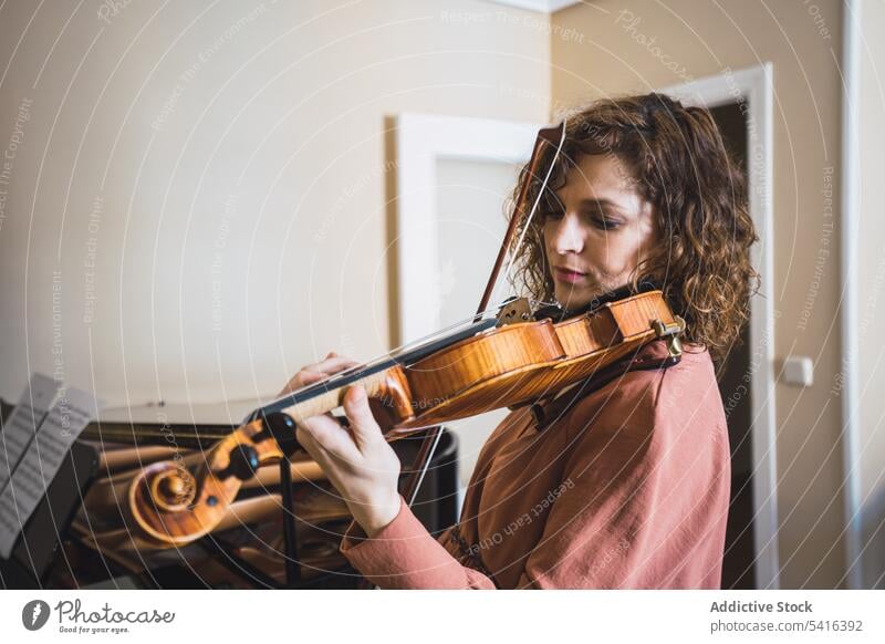 Pregnant woman playing on violin near piano in room pregnant musician attractive young curly hair beautiful closed eyes female belly sitting lifestyle relax