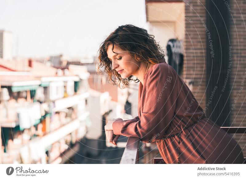 Attractive woman on balcony attractive young curly hair beautiful city urban female positive lifestyle relax casual leisure summer home elegant fashion pleasure