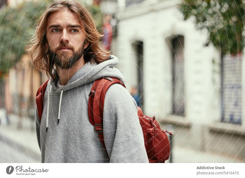 Handsome man walking on street hairstyle backpack mustache hoodie adult handsome lifestyle stubble happiness bearded model young confident male casual looking