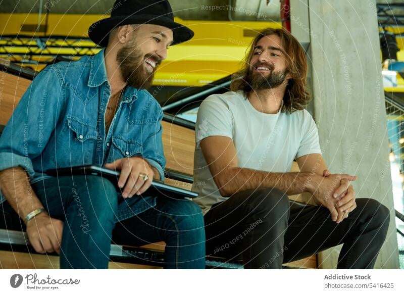 Men sitting on stairs and lively chatting men handsome friendship smiling discussing talking enjoying adult lifestyle together mustache happiness bearded model