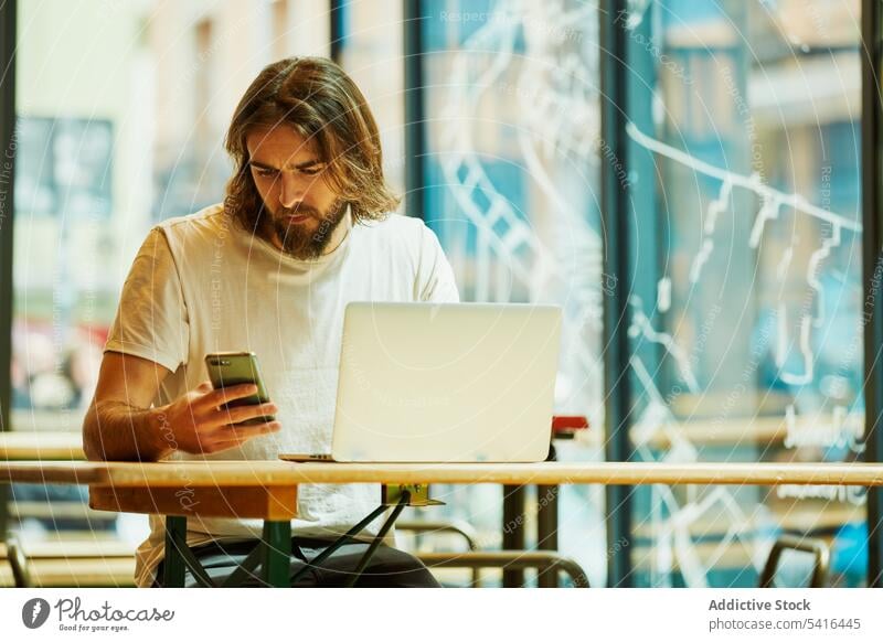 Handsome man using phone and laptop handsome mustache working adult lifestyle stubble hairstyle happiness bearded model young confident professional notebook