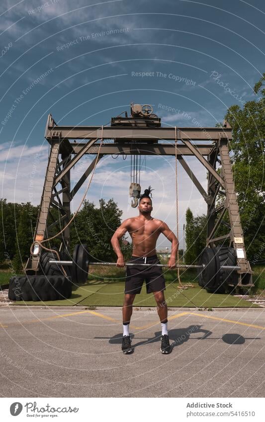 Black guy with barbell in outdoor gym man lifting exercise workout shirtless african american clouds sky male fitness weight training strength power sport