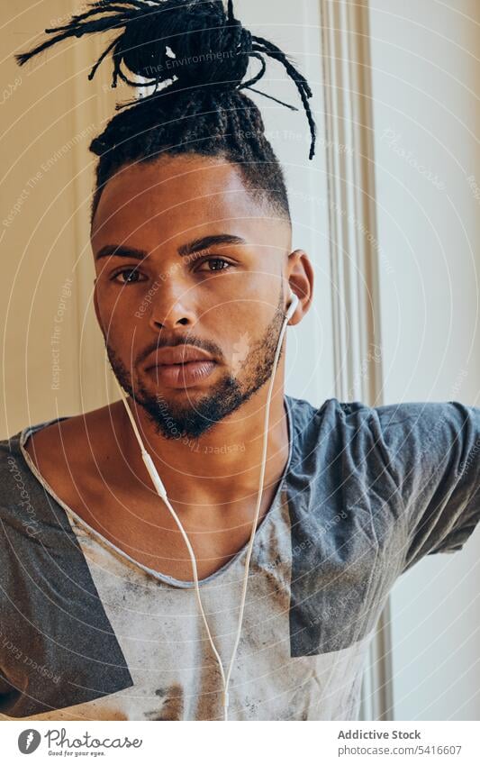 African American man looking out window ethnic braided hairstyle pigtails creative earphones music young male african american person handsome attractive
