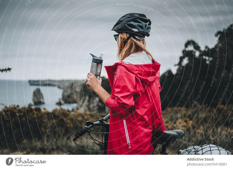 Female bicyclist holding sport bottle woman bicycle helmet female adult person active sportive thoughtful standing watching drinking contemplating lifestyle