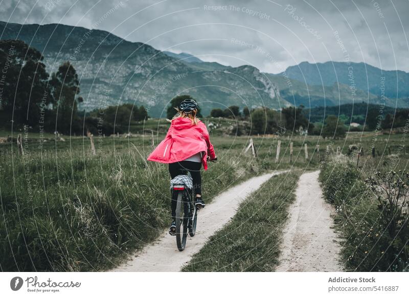 Female cyclist riding on mountain road woman bicycle helmet rocky back view landscape female adult person active sportive alone cycling lifestyle bike travel