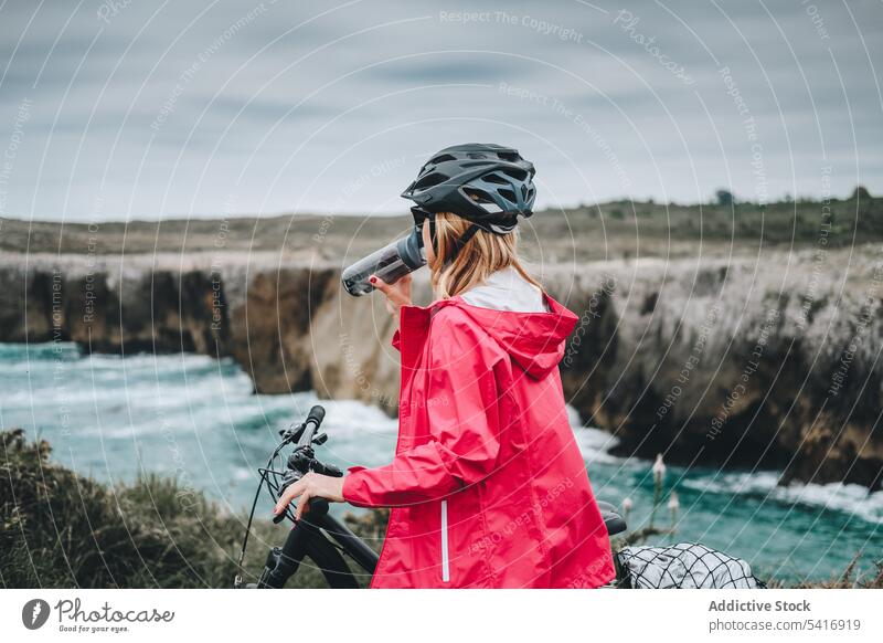Female bicyclist holding sport bottle woman bicycle helmet female adult person active sportive thoughtful standing watching drinking wearing contemplating