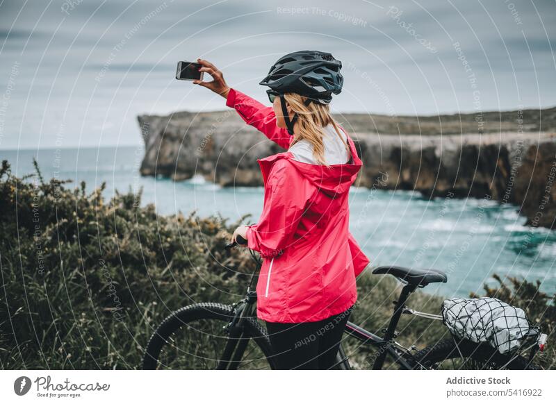 Female taking photos on cliffs woman helmet landscape mountain rock travel extreme adult person active blonde brave sportive contemplating standing shooting