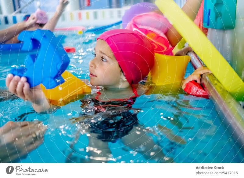Ethnic girl with water wings in swimming pool playing park inflatable ethnic toy fun child kid joy happy little vacation rest relax leisure armbands activity