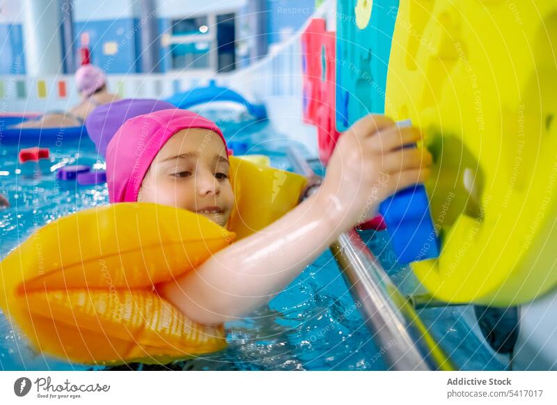Ethnic girl with water wings in swimming pool playing park inflatable ethnic toy fun child kid joy happy little vacation rest relax leisure armbands activity